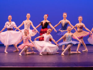 Students from the Berks Ballet Theatre curtsy on stage in front of a blue background